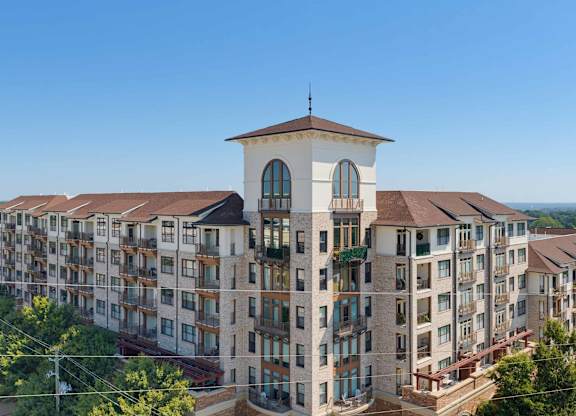 Aerial of the building's tower, with tall arched windows, juliet balconies, and residence balconies on both wings.