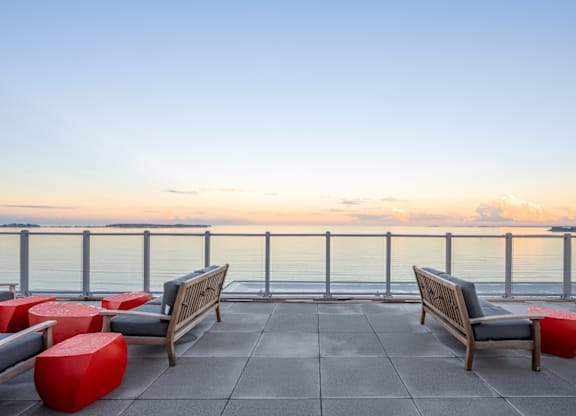 A sunset view from a rooftop with a bench and a table.