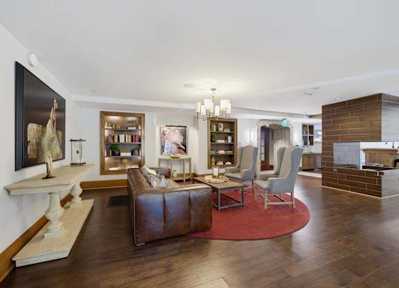 Clubroom lounge with a sofa, two wing chairs, lit built-in bookshelves, a chandelier, and a tile-clad fireplace.