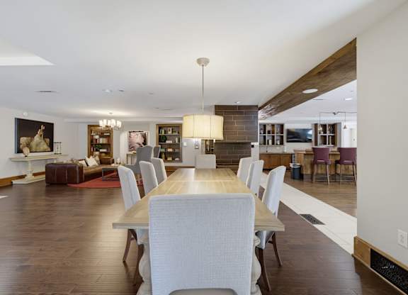 Clubroom with a long dining table, lounge seating at the far end, a tile fireplace column, and a bar to the right.