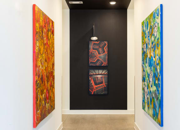three paintings in a room with a black wall and a light fixture