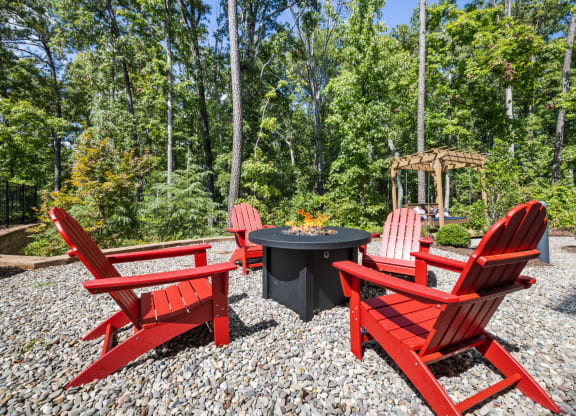 a group of red chairs sitting around a firepit