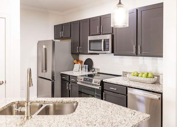 A kitchen with a sink, refrigerator, oven, and microwave.