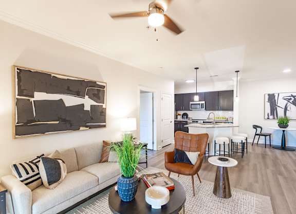 A living room with a couch, a chair, a table, and a painting on the wall.