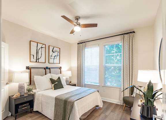 A bedroom with a bed, nightstand, and a ceiling fan.