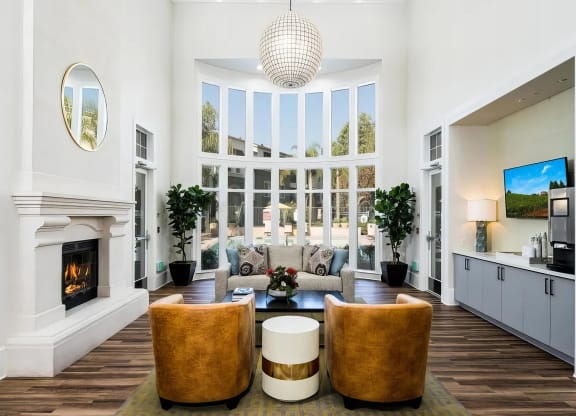 Clubhouse lounge at Amerige Pointe with a fireplace, leather barrel chairs, and a two-story arched window wall.