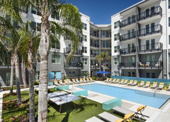 Courtyard Pool Surrounded by Lounge Chairs, Ping Pong Tables, and Palm Trees