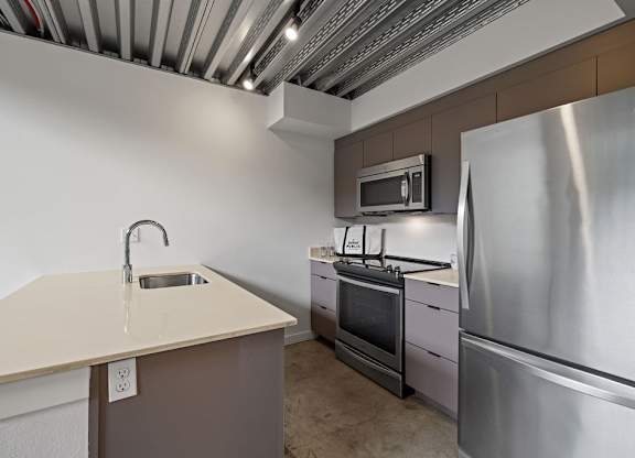 A kitchen with a stainless steel refrigerator, microwave, and oven.
