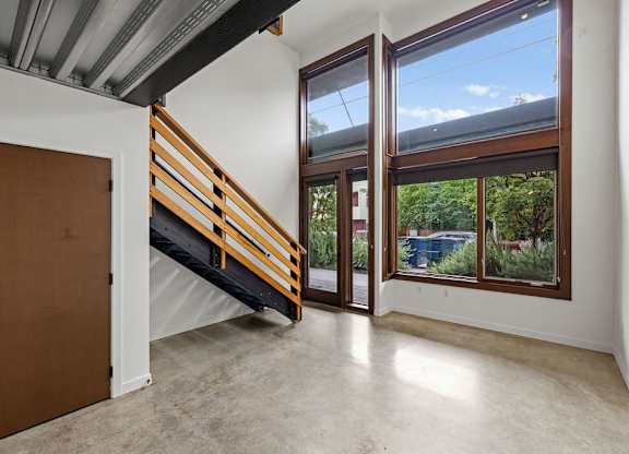 A room with a brown door and a staircase leading to a balcony.