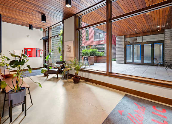 A room with a wooden ceiling and floor, and a large window with a view of the outside.
