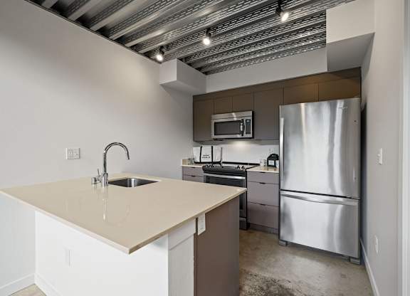 A kitchen with a sink, stove, and refrigerator.