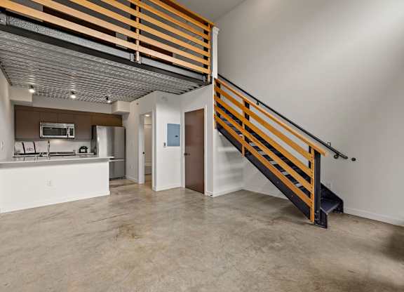 A room with a staircase and a kitchen area.