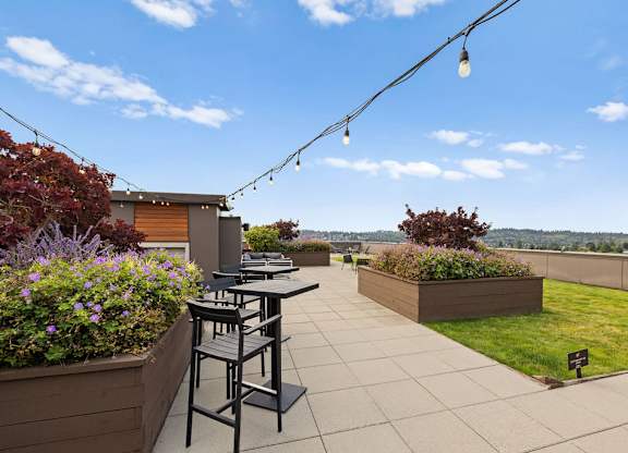 A patio with a table and chairs overlooking a grassy area.