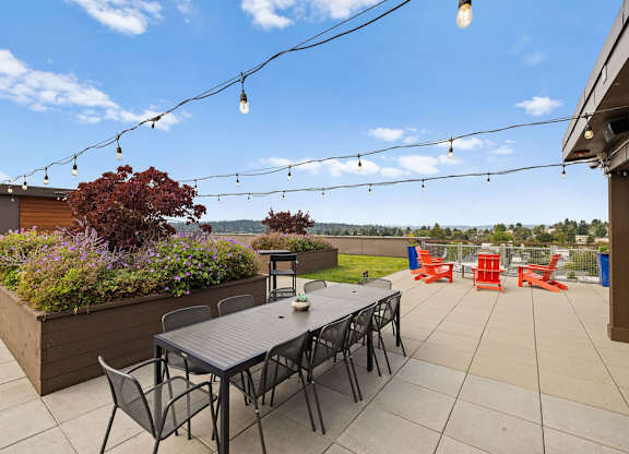 A patio with a table, chairs, and string lights.