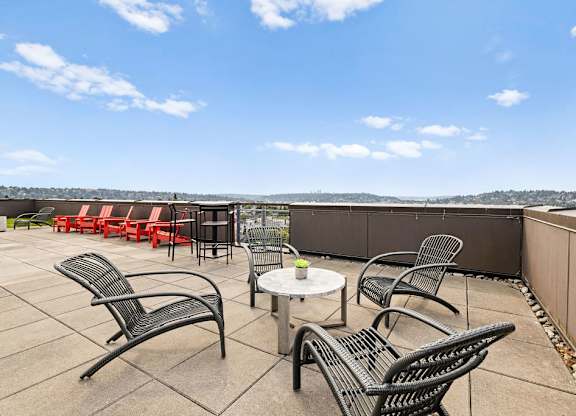 A patio with black metal chairs and tables overlooks a cityscape.