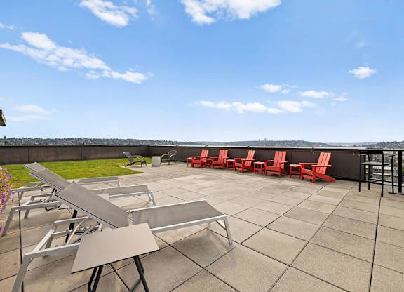 A patio with tables and chairs overlooking a grassy area.
