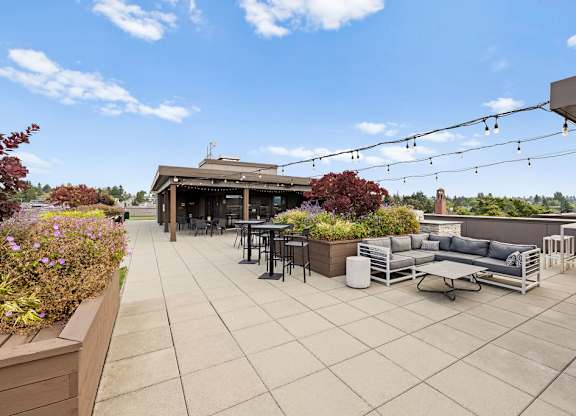 A patio with a table and chairs is surrounded by plants.