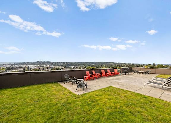 A patio with red chairs and a table is set up on a grassy area.
