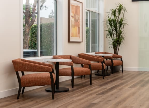 a seating area with tables and chairs in a room with large windows