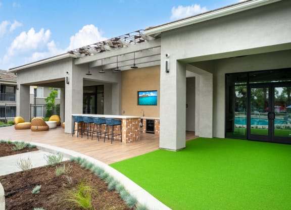 a patio with a bar and green grass in front of a house