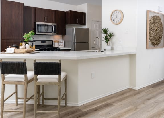 an open kitchen with a large island with two stools in front of a counter