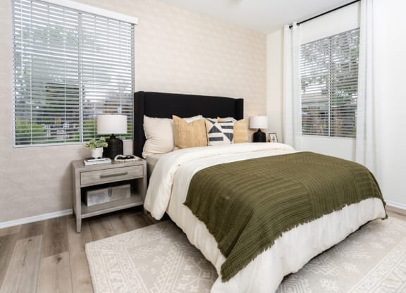 a bedroom with a bed and two windows