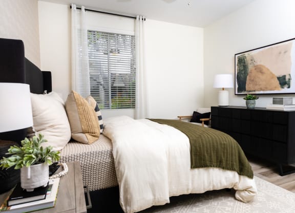a bedroom with a bed and a dresser and a window