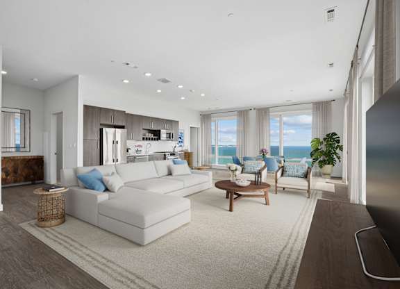 Penthouse great room with seating, a dining area and a kitchen along one wall, with windows out to open water.