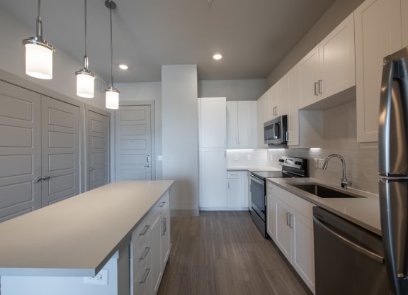 Island Kitchen with Quartz Countertops, White Cabinetry, and Pendant Lights