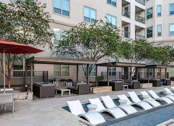 Outdoor Pool Area with Modern Chaise Lounges and Shaded Seating