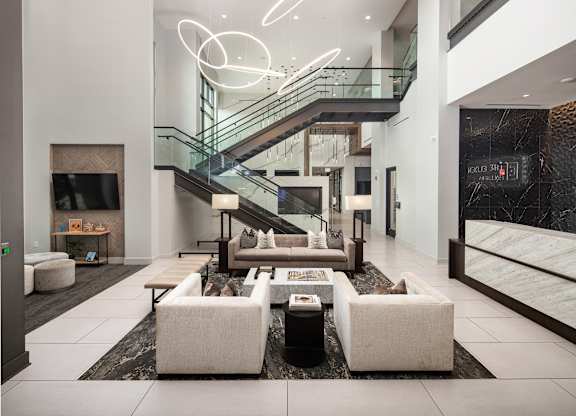 A modern living room with a staircase and a glass railing.