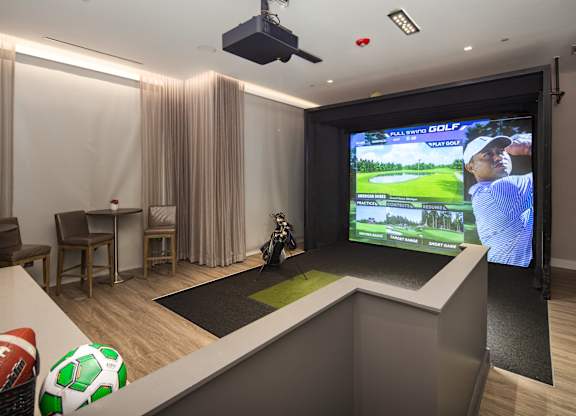A room with a television screen showing a golf game and a ball on the floor.