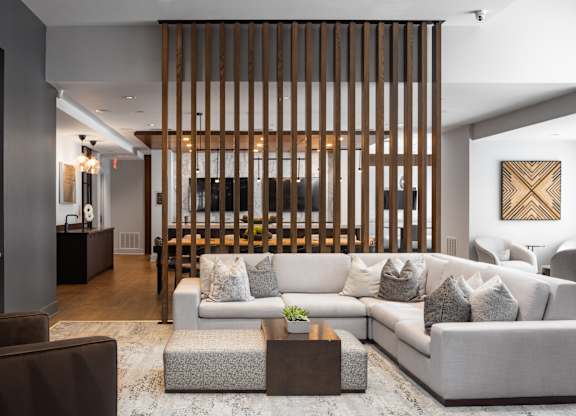 A modern living room with a large couch and a wooden slat wall.