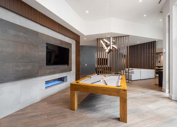 A billiard table in a room with a fireplace and a TV.