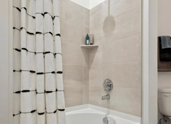 Shower and Bathtub Combo with Beige Wall Tiles and Storage Shelf