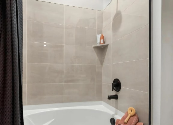 Beige Tile Bathtub Wall with Shower Fixtures and Built-In Shelf