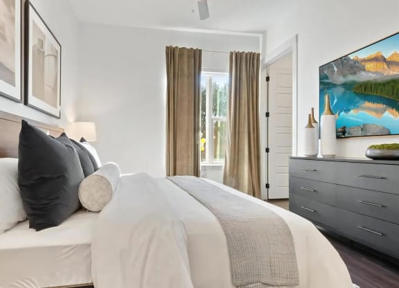 Bedroom with Framed Artwork, Dresser, and Wall-Mounted TV