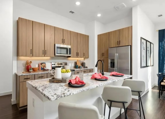 Apartment Kitchen with Granite Island, Bar Stools, and Stainless Appliances