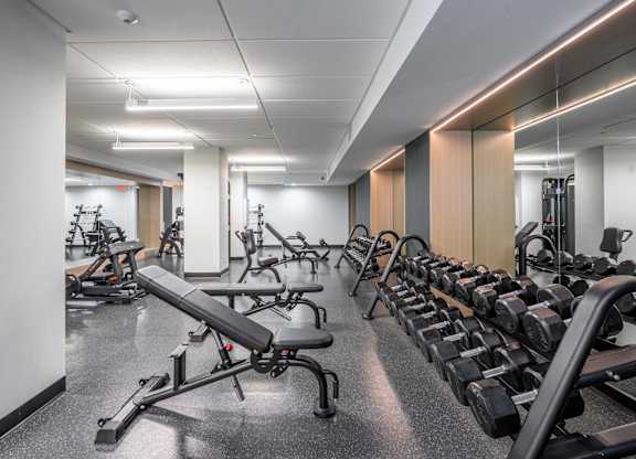 A gym with a variety of equipment including dumbbells and weight machines.