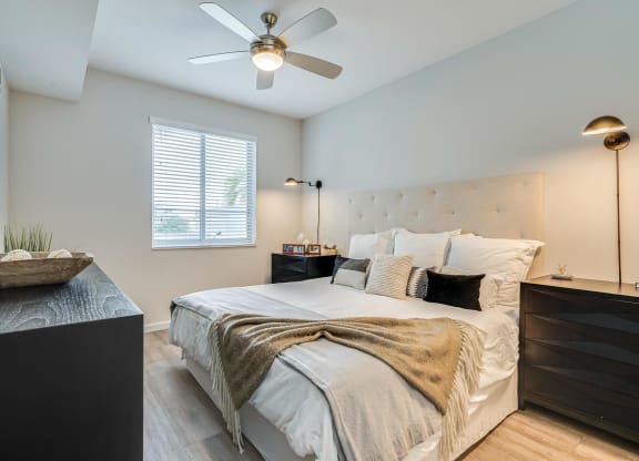 Bedroom Featuring Ceiling Fan, Tufted Headboard, and Window with Blinds