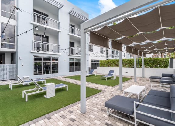 Ground-Level Green Space with Lounge Chairs and Walkways Next to Residential Windows