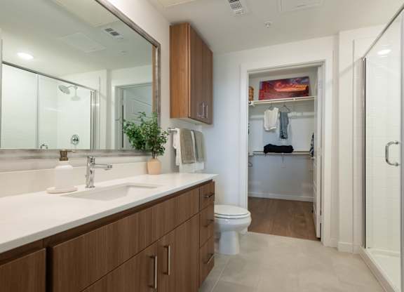 A bathroom with a white sink and brown cabinets.