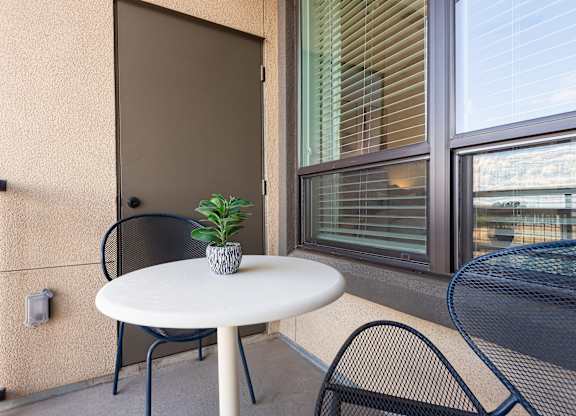 A small table with a plant on it sits on a balcony.