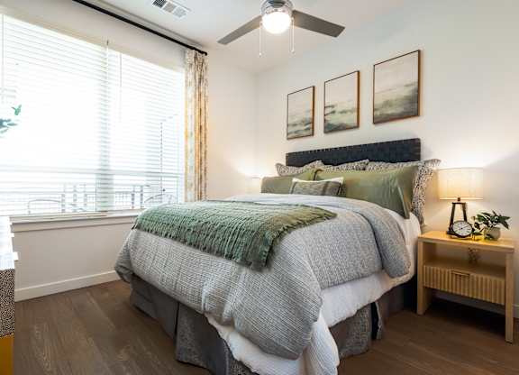A bedroom with a large bed and a ceiling fan.