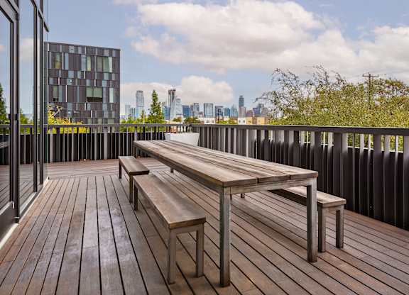 A wooden deck with a bench and a table with a metal frame.