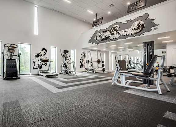 A gym with a variety of equipment including treadmills, weights, and exercise machines.