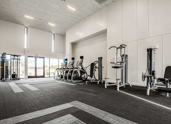 A gym with a variety of equipment including treadmills, weights, and exercise machines.