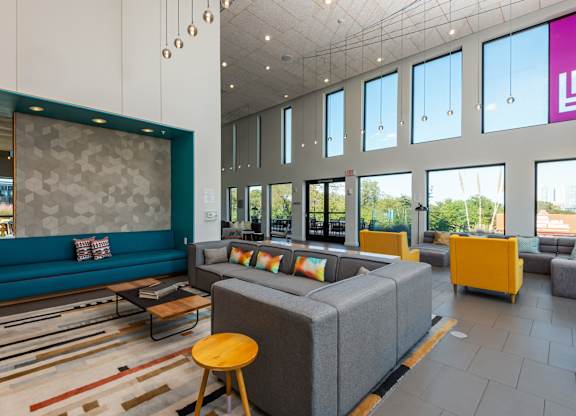 A modern living room with a grey sofa and a yellow stool.