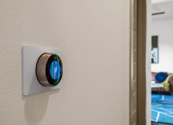 A wall-mounted thermostat with a blue light on it.