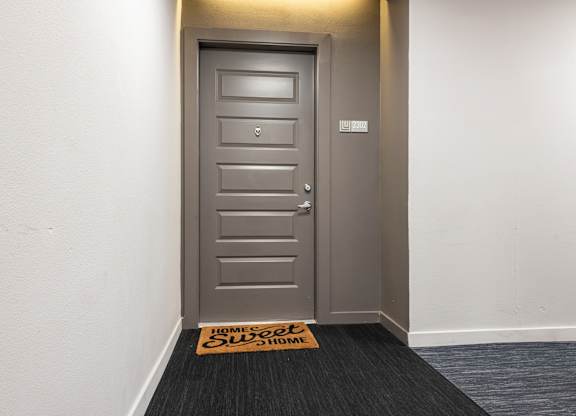 A grey door with a sign on the floor that says